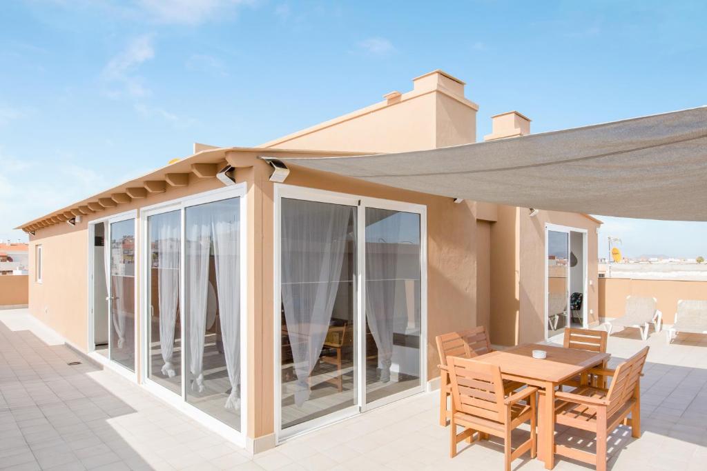 a patio with a wooden table and a patio umbrella at Ático deluxe Corralejo centro in Corralejo
