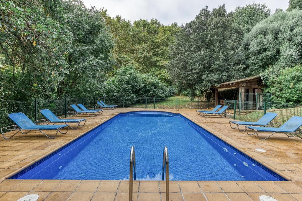 ein Schwimmbecken mit blauen Stühlen in der Unterkunft Can Tapis in Santa María de Camós