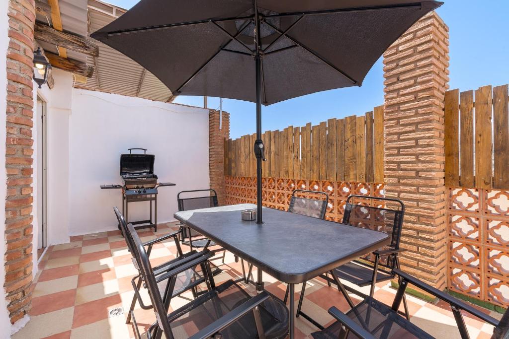 a table and chairs with an umbrella on a patio at Casa Rústica in Vélez de Benaudalla
