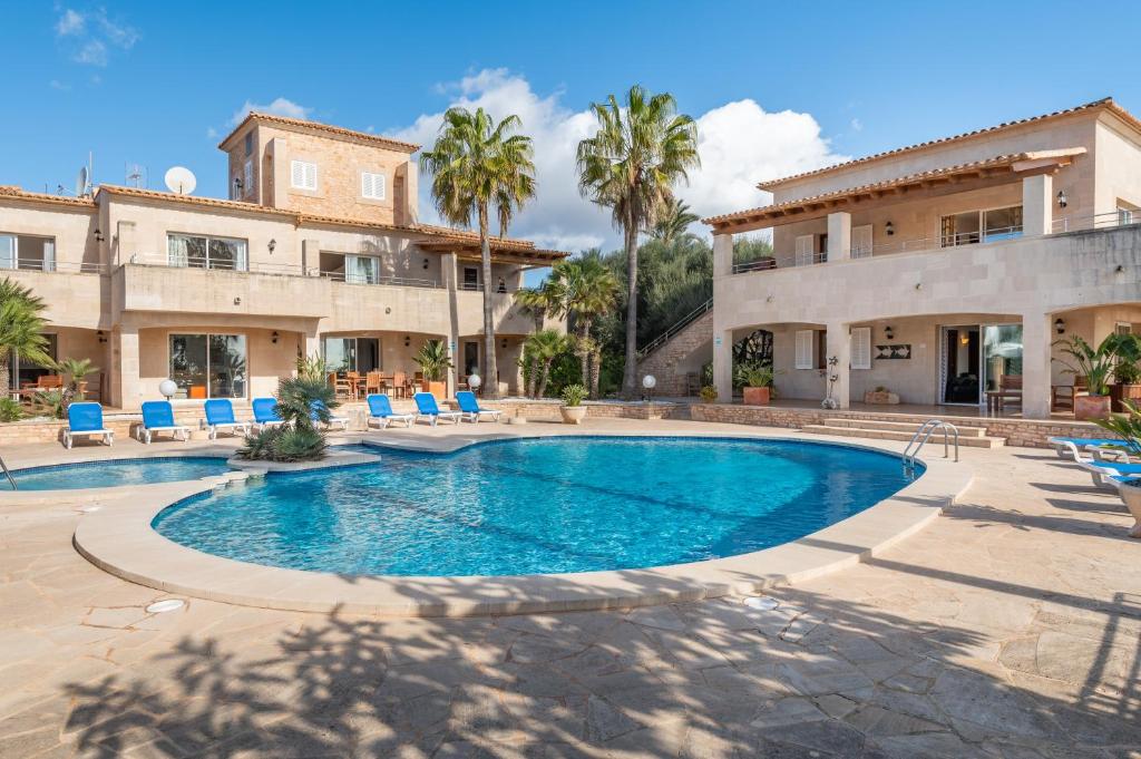 a pool in front of a house with palm trees at Pedrassa Gran Superior in Cala Santanyi