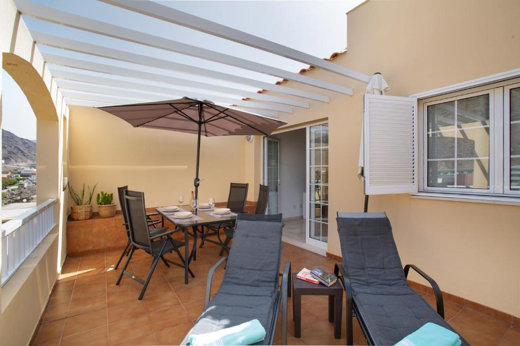 a patio with a table and chairs and an umbrella at Mangueros Suite 36 Puerto de Mogán in Puerto de Mogán