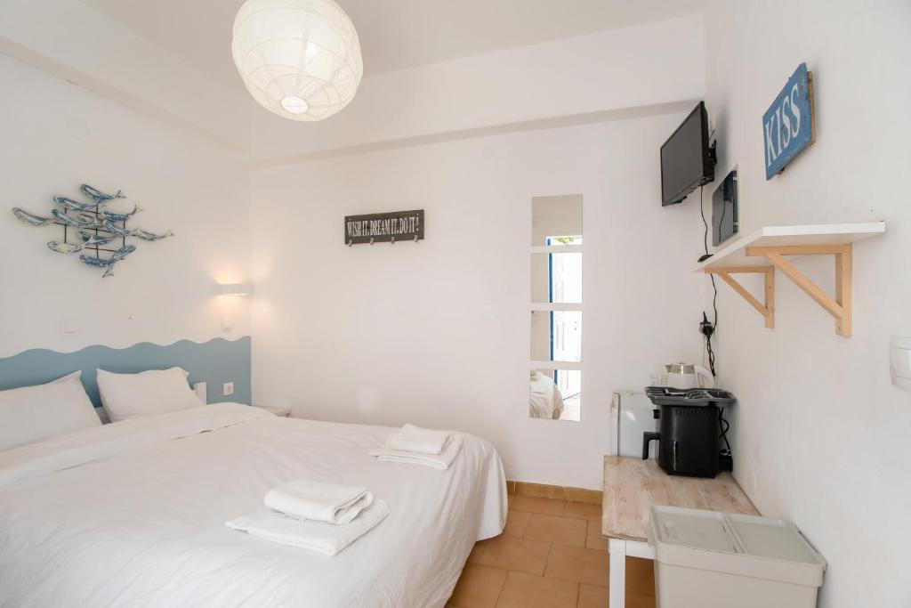 a bedroom with a white bed and a tv at Livadia Seaside Studios 6 in Parikia