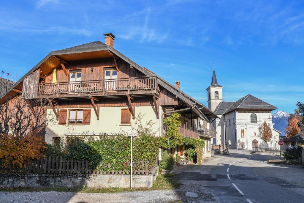 a large wooden house with a balcony and a church at Gîte Yveco in Châteauneuf