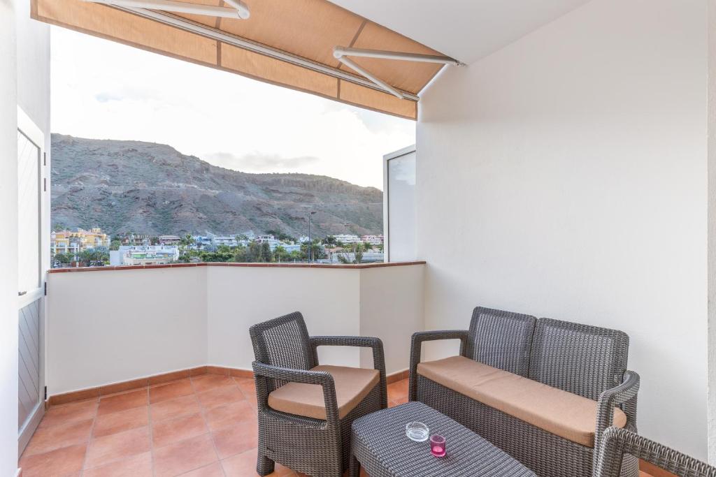 a balcony with two chairs and a table and a window at Vv Velero in Puerto de Mogán