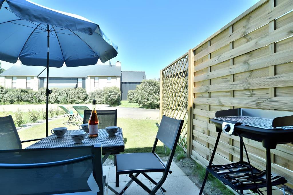 a patio with an umbrella and a table and chairs at Maison Les Flots De Port-mer in Cancale