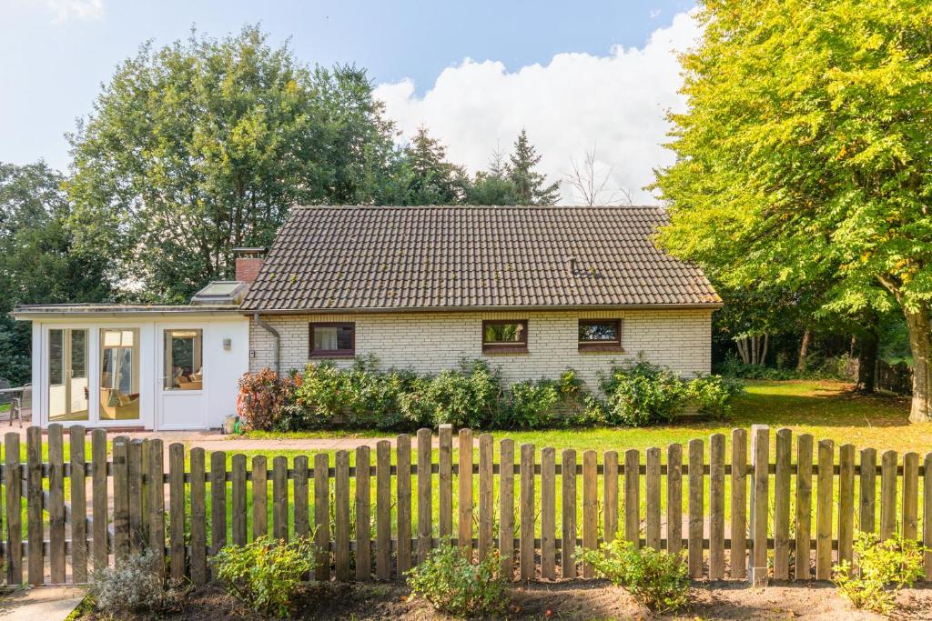 a small white house with a wooden fence at Heidehaus in Enge-Sande