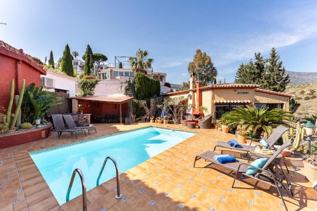 a swimming pool with chairs and a house at Cosy house jacuzzi wifi pool view in Mijas