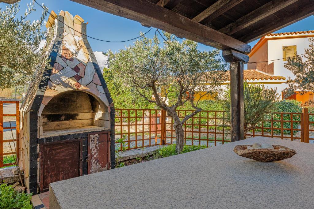 an outdoor pizza oven in a yard with a fence at Domus Dejana in San Teodoro