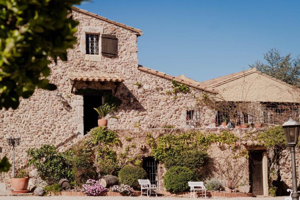 an old stone building with chairs and flowers at Masia Mimosa Jardin in Darnius