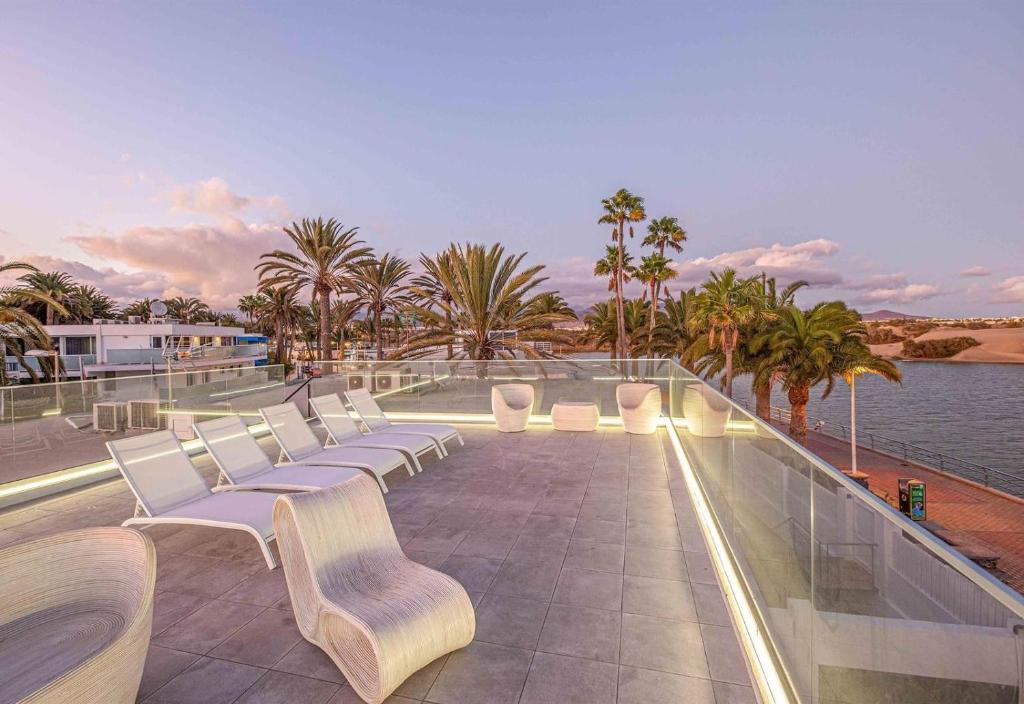 a row of white chairs sitting on a roof at Seafront villa with jacuzzi in Maspalomas