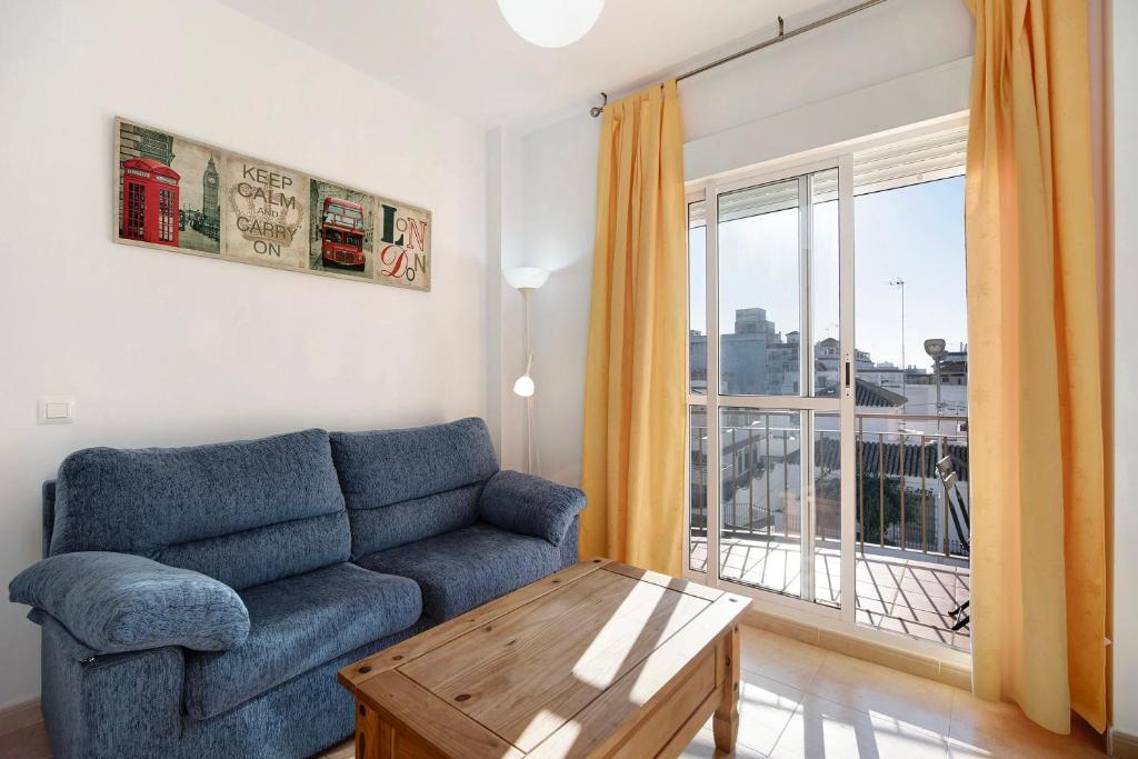 a living room with a blue couch and a window at Apartamento Merce in Rota