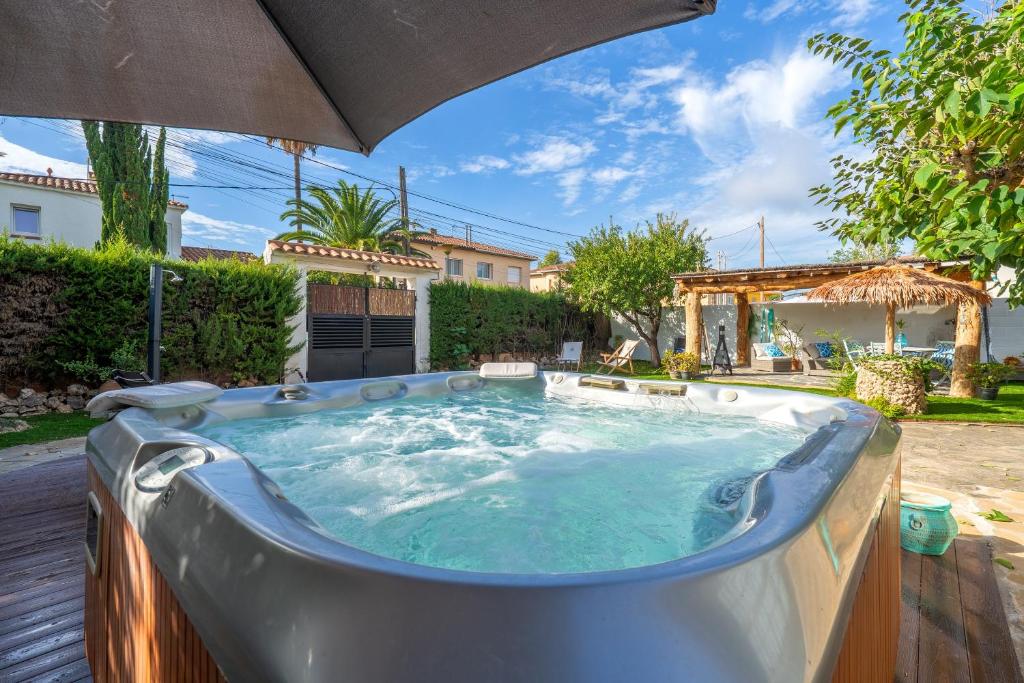 a hot tub in a yard with an umbrella at Beach house in Torredembarra