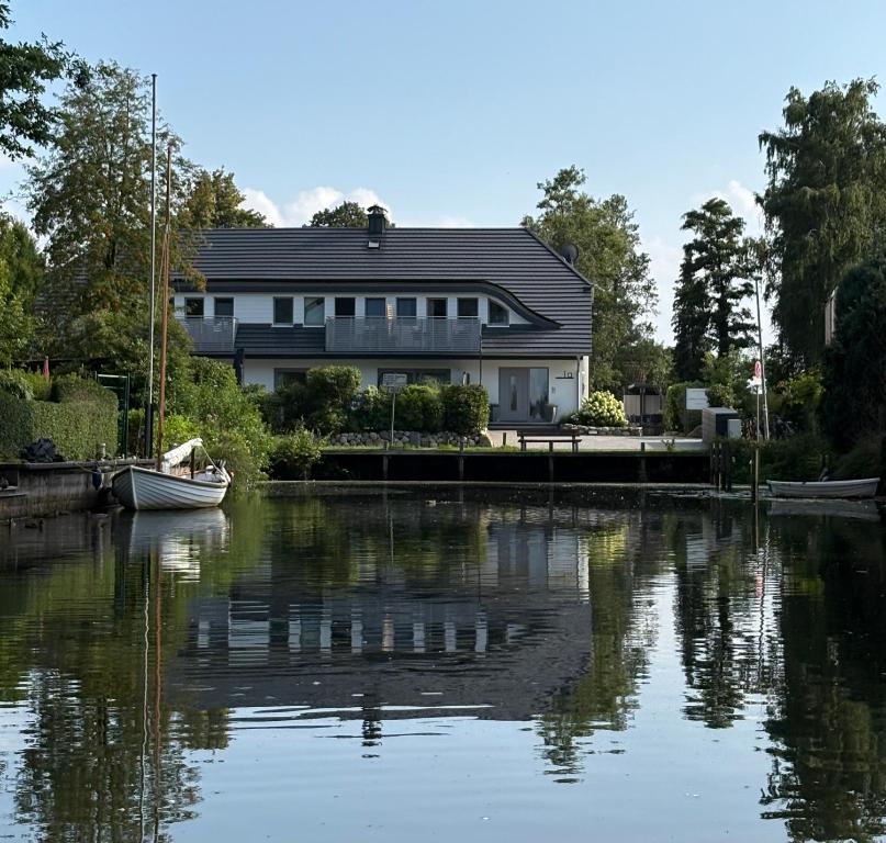 a house on the water with a boat in front of it at Landhotel Strandallee in Wunstorf