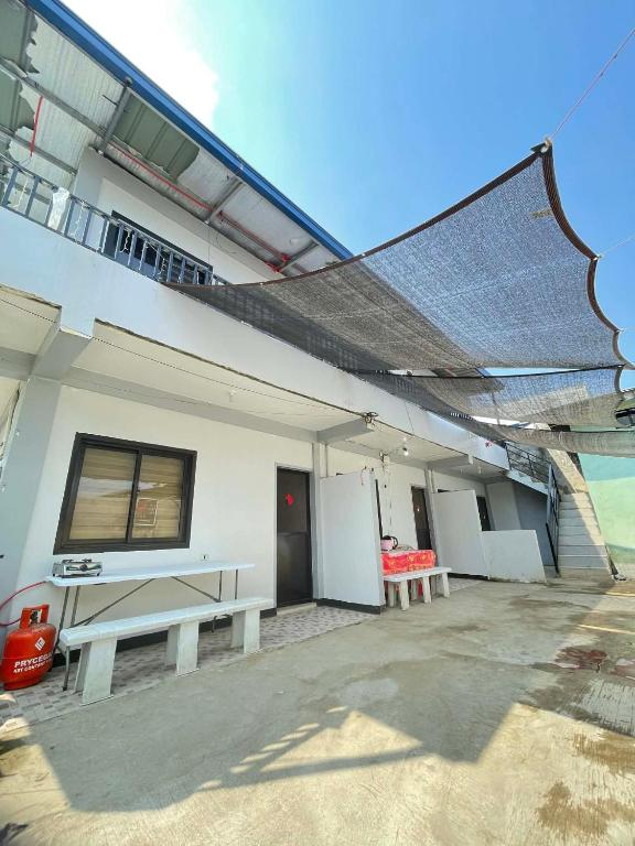 ein weißes Gebäude mit zwei Bänken und einem Tisch in der Unterkunft ACA Transient House in Nasugbu
