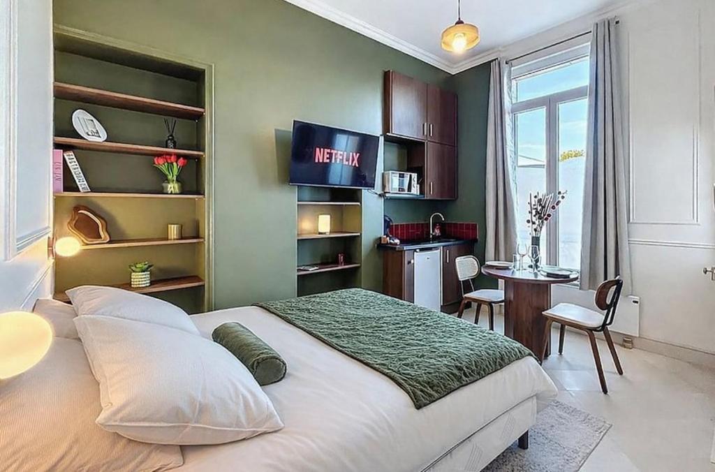a bedroom with a large bed with a desk and a kitchen at Le Studio du Chateau in Bréviandes