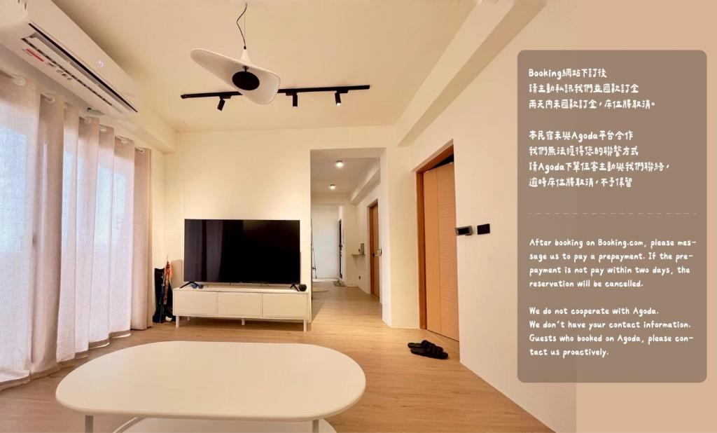 a living room with a white table and a tv at Sunset Hostel in Lanyu