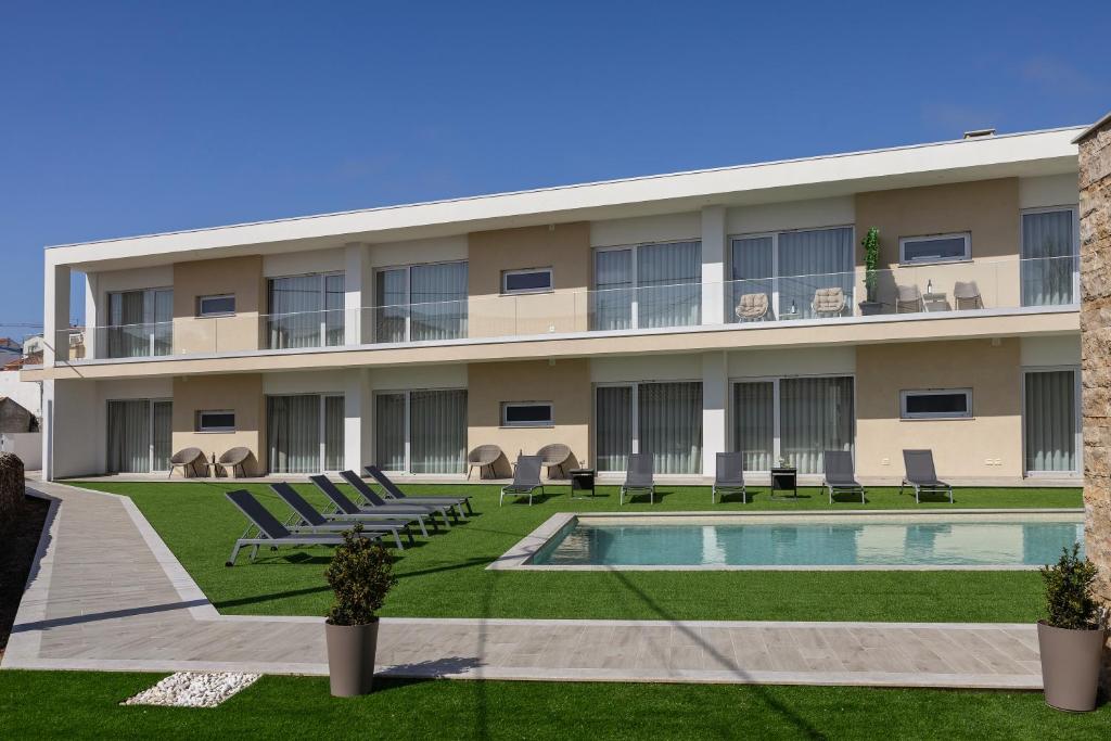 an apartment building with a swimming pool and chairs at Terra - B&P Infinity House in São Martinho do Porto