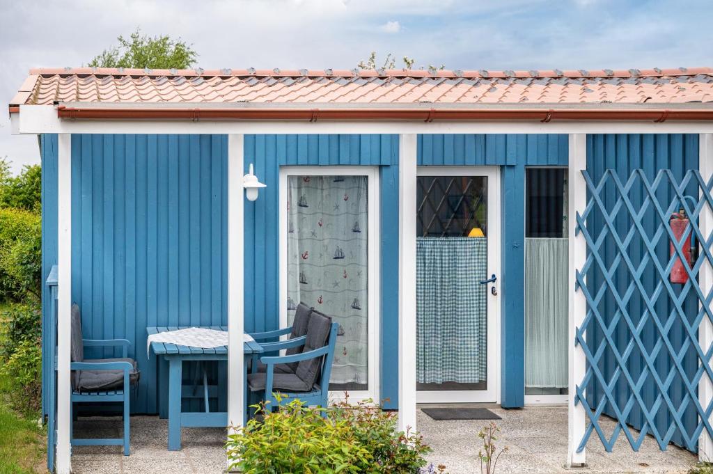 a blue shed with a table and chairs in a yard at Möve Aba Bungalow 66 in Rerik
