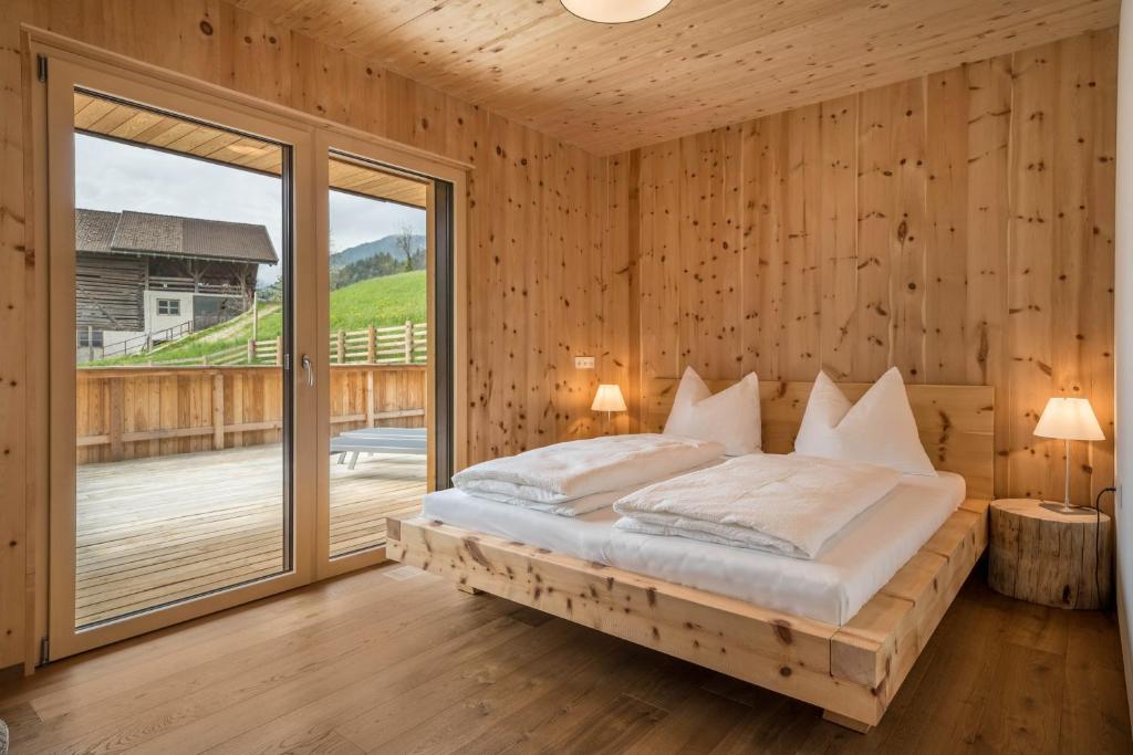 a bedroom with a bed and a large window at Naturapartments Alpreid Zirbe in San Pancrazio dʼUltimo