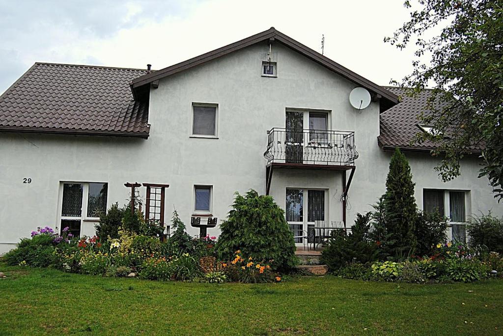 a white house with a balcony and a yard at Gospodarstwo Agroturystyczne E K Szabowscy in Jeżewo
