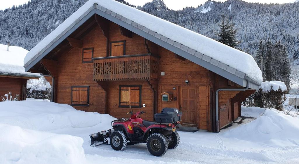 a atv parked in front of a log cabin in the snow at Chalet Du Saix - Sauna in La Chapelle-dʼAbondance