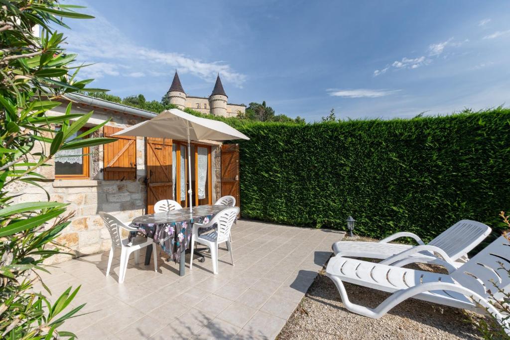 a patio with a table and chairs and a castle at Les Sources Gîte La Remise in Chambonas