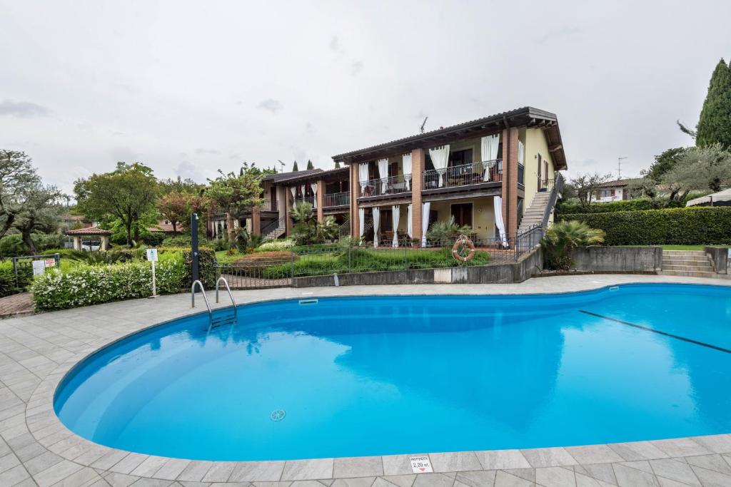 a large blue pool in front of a house at Residence La Piopa in Polpenazze del Garda