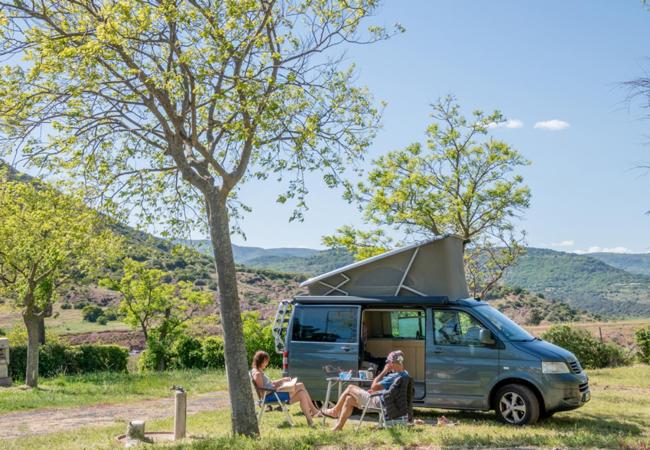 three people sitting at a table in front of a van at Camping Onlycamp Les Peupliers du Lac in Chindrieux