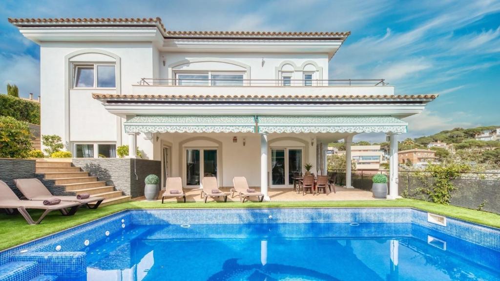 a villa with a swimming pool in front of a house at Costacabana - Villa Madison in Lloret de Mar