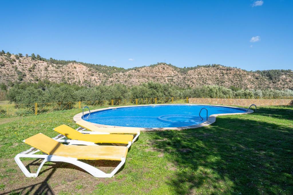 a swimming pool with chairs and mountains in the background at Mas de Sisco in Flix
