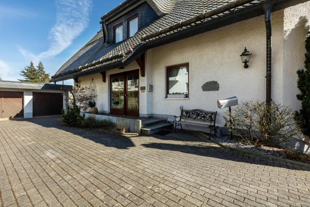 a house with a bench on a brick driveway at Appartmenthaus Felicitas in Willingen