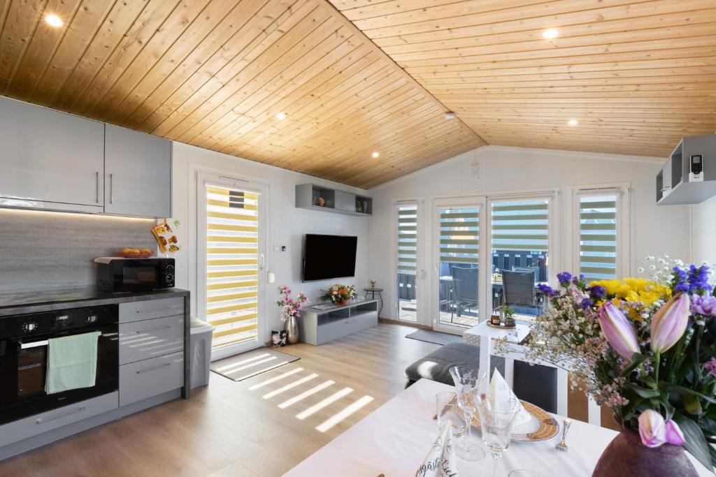 a kitchen with a wooden ceiling and a table with flowers at Madera Concordiasee in Friedrichsaue