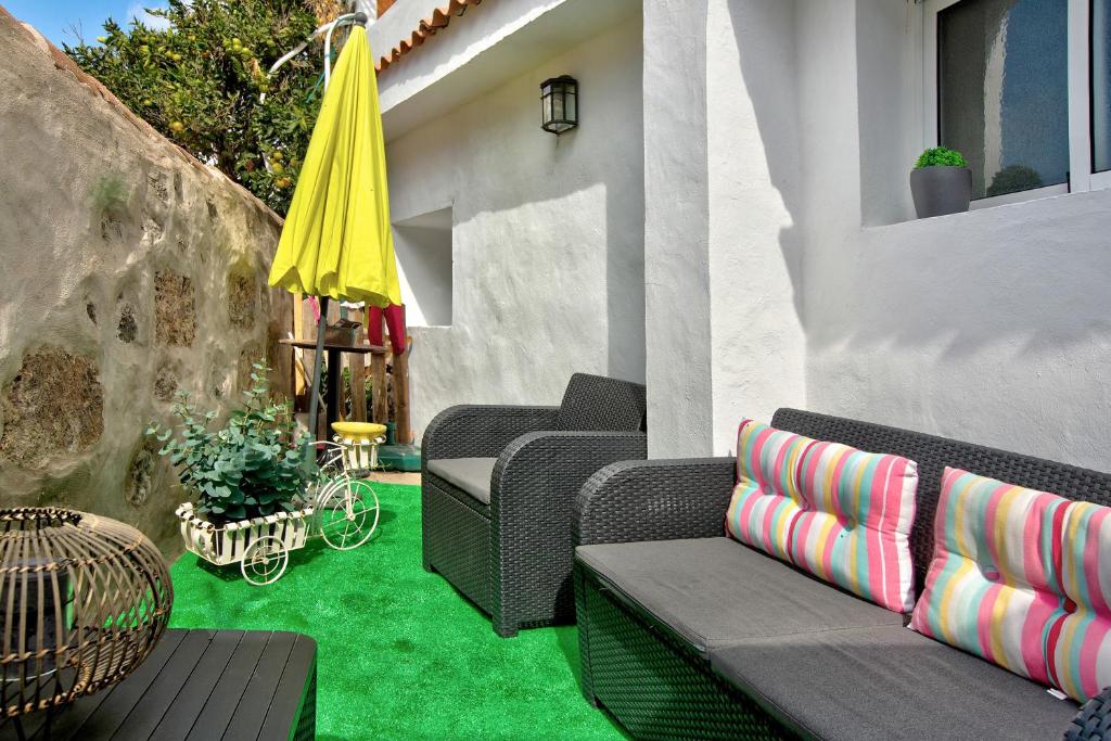 a patio with chairs and a yellow umbrella and green grass at Casa del Callejon in Tejeda