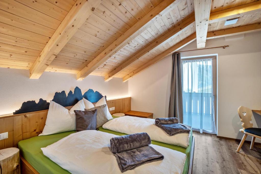 two beds in a room with a large window at Krämerhof Apt Villnösser Geisler in Rodengo