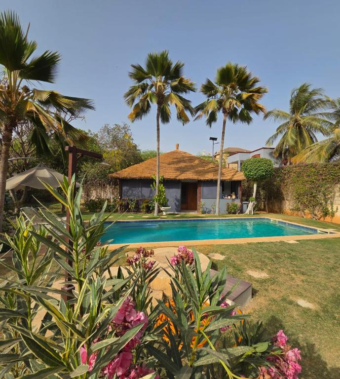 a villa with a swimming pool and palm trees at Jardin d'Afrique, Saly in Saly Portudal