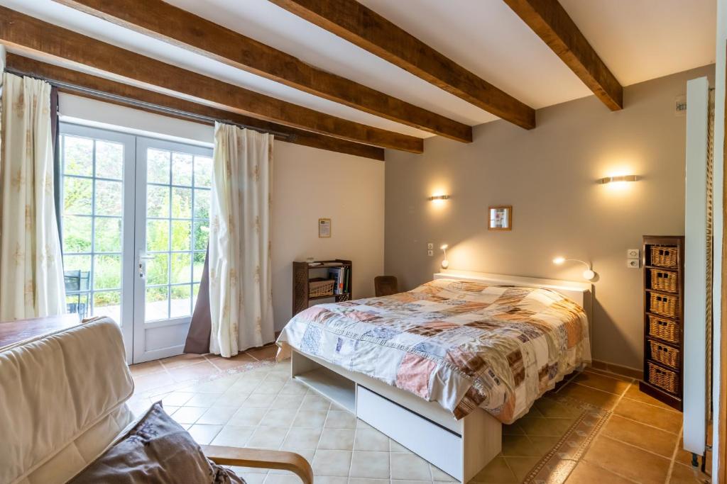 a bedroom with a bed and a large window at Chambre Millepertuis in Auriac-du-Périgord