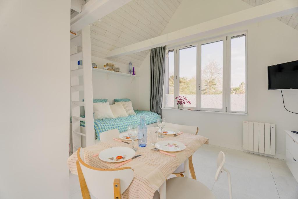 a white dining room with a table and chairs at La Cabane des Goélands Rieurs in Dinard