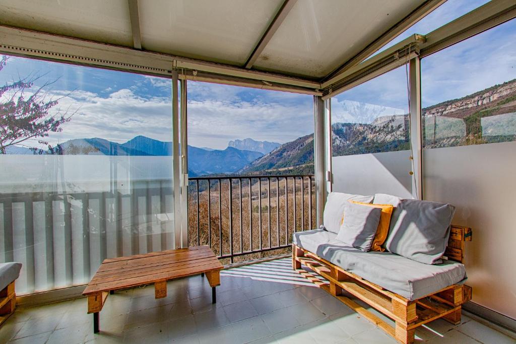 a balcony with a chair and a table and mountains at Gîte Ludomi in Vercheny