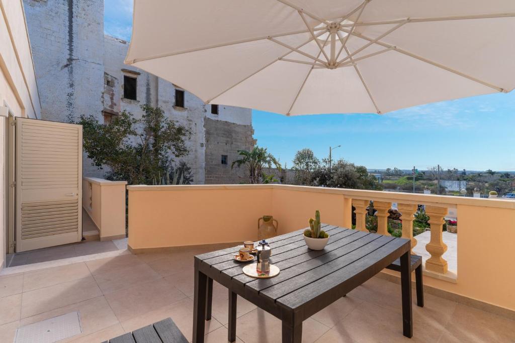 a patio with a wooden table and an umbrella at Casa vacanza Sotto La Lizza in Alezio
