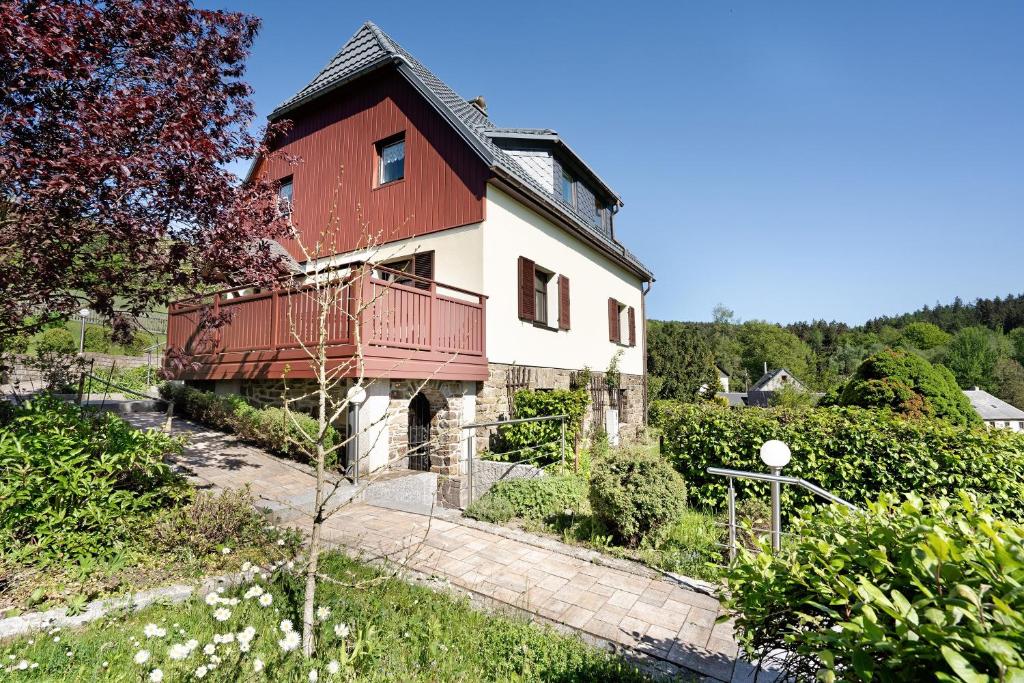 a red and white house with a balcony at Ferienhaus Pöhlbergblick Schindelba in Großrückerswalde