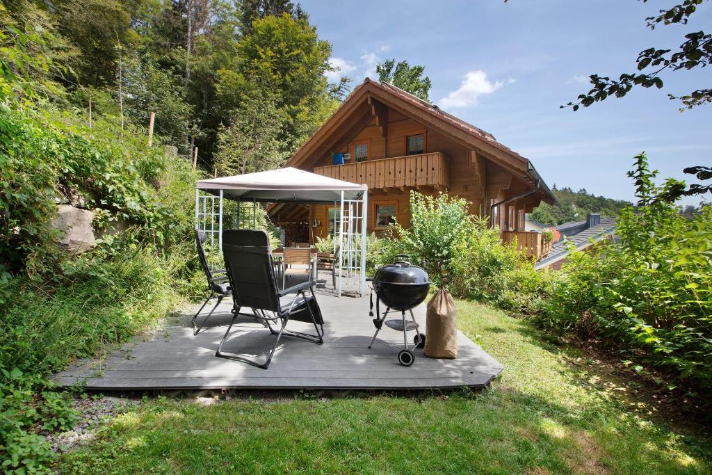 a grill and chairs on a deck in front of a cabin at Ferienhaus Sankt Peter in Wittenschwand