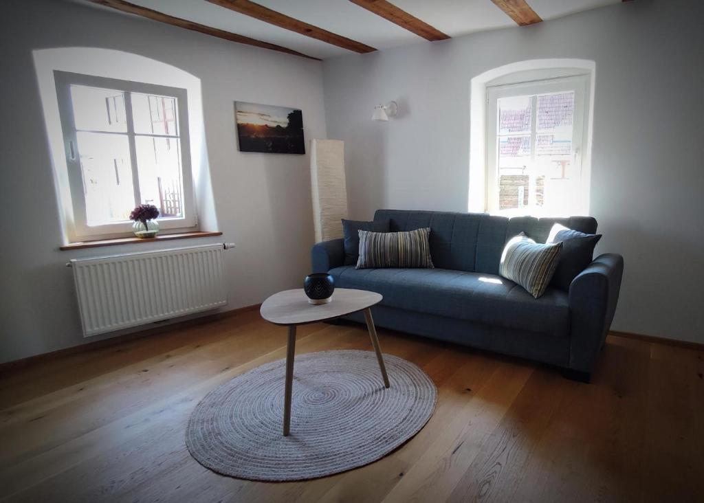 a living room with a blue couch and a table at Ferienwohnung La Maison Palatinate in Kapsweyer