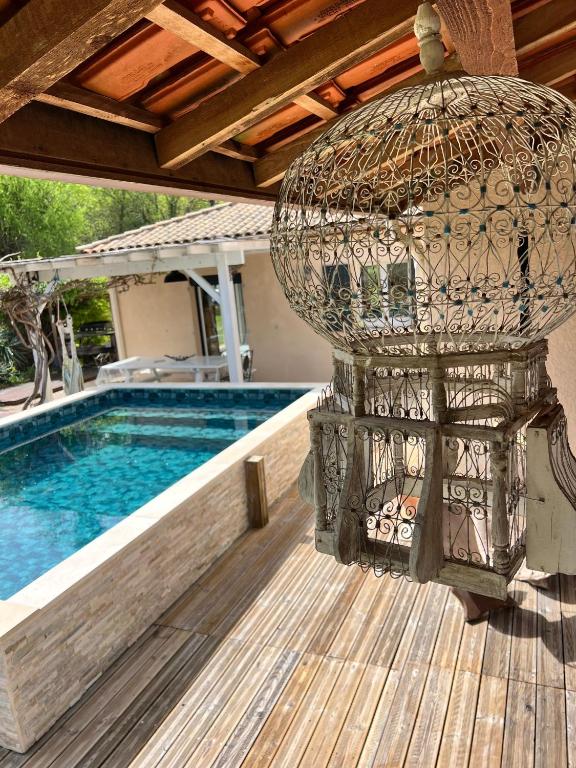 a bird cage sitting on a deck next to a pool at Petit coin de paradis Périgourdin in Montrem