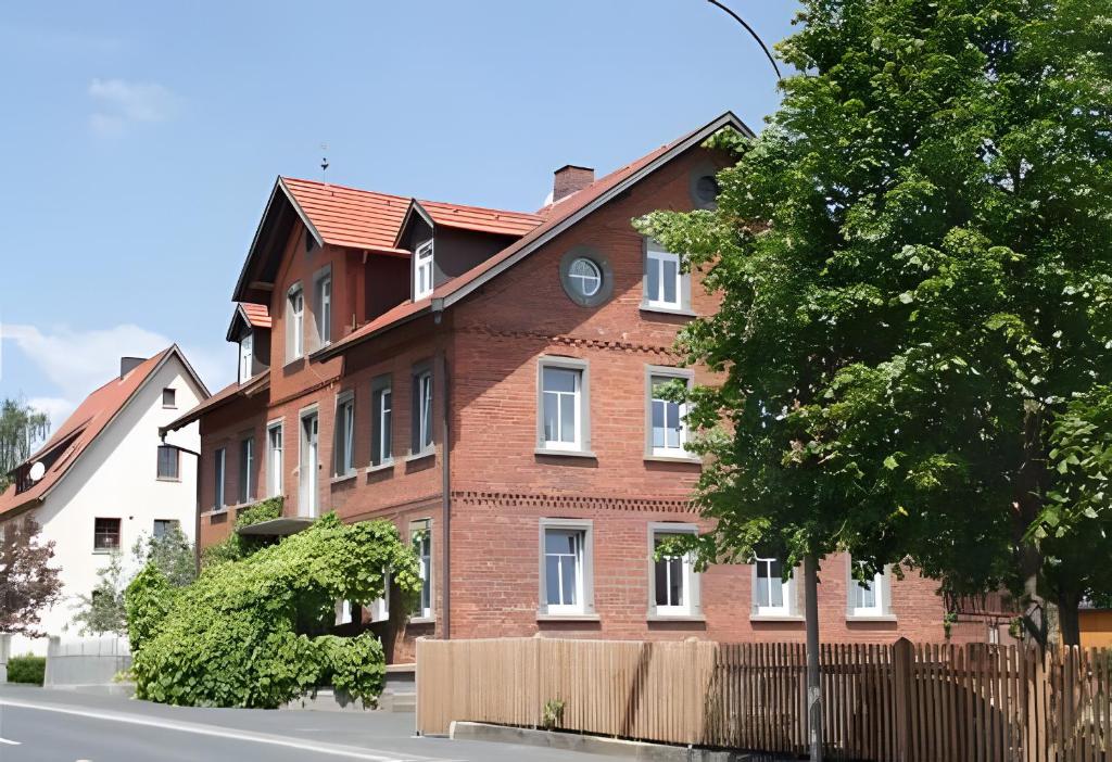 a brown brick building with a fence and a tree at Ferienwohnung Zur Eisenbahn in Fladungen