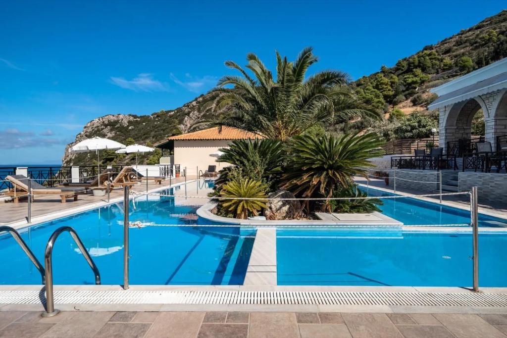 a pool with palm trees and the ocean in the background at Sunset Premium Studio 13 in Lefkada