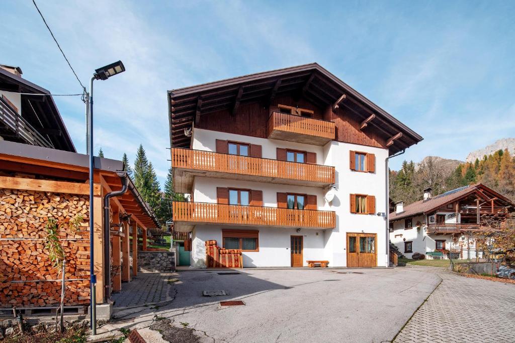 a white building with a wooden roof at Appartamenti Adriano Minotto in Falcade