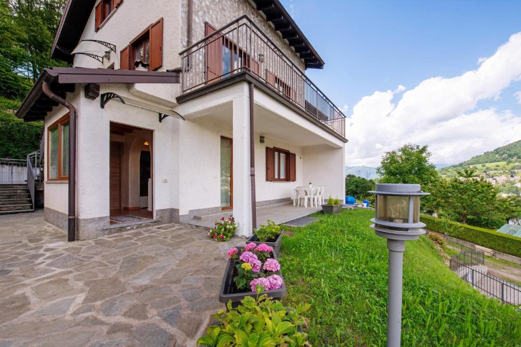 a house with a balcony and flowers in the yard at Loft bellavista in San Fedele Superiore
