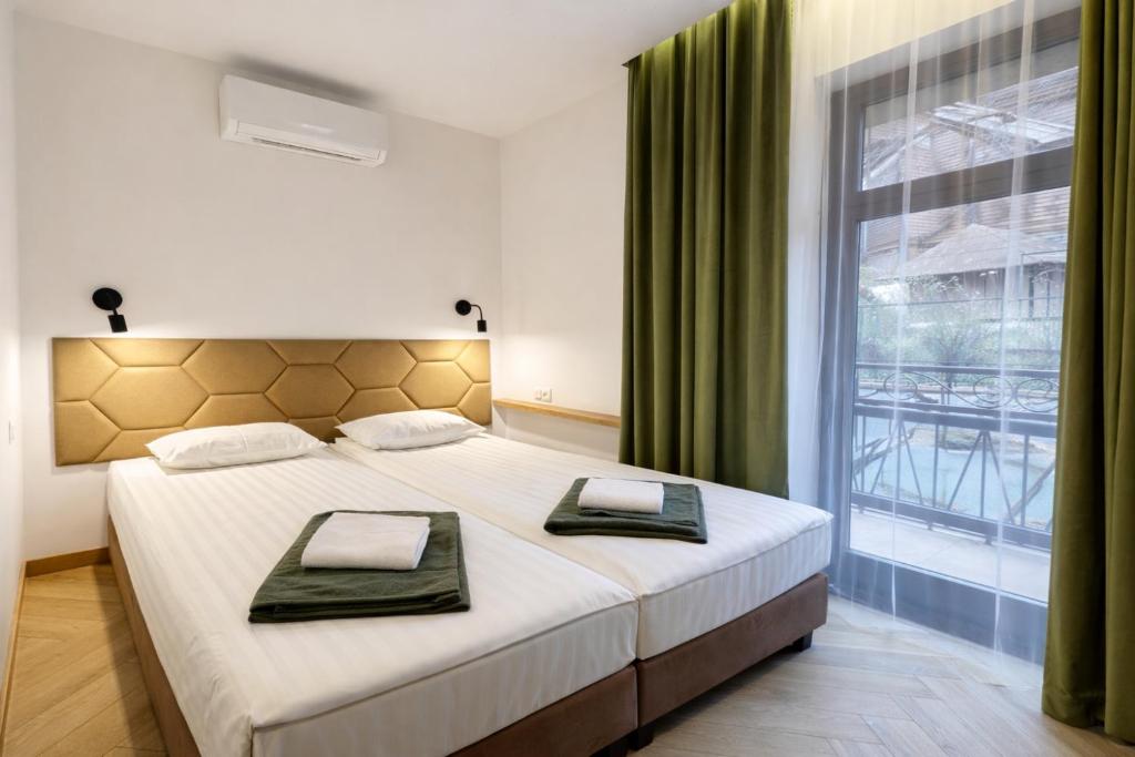 a bedroom with a large bed and a large window at Willa Deptak in Krynica Zdrój