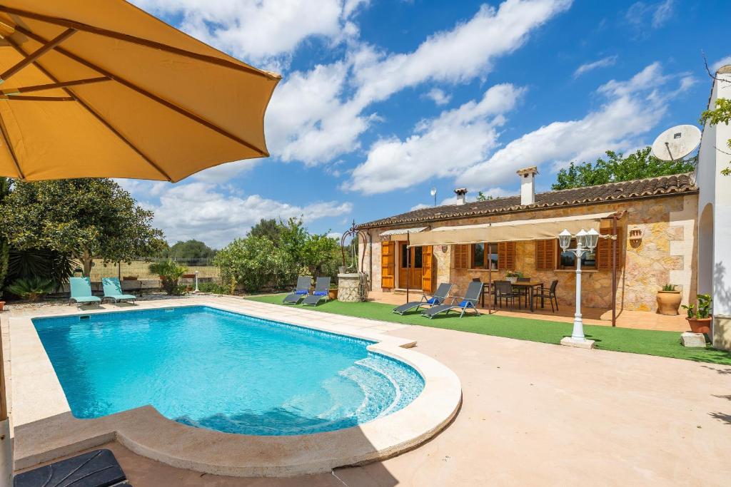 a pool with an umbrella next to a house at Casita Rafal Roig in Maria de la Salut