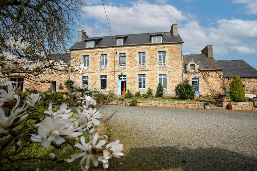 an old stone house with white flowers in front of it at Gite 8 personnes in Bégard
